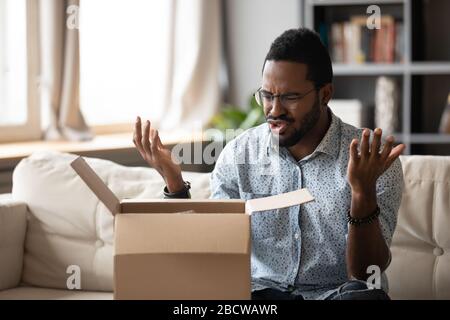 Frustrierter biracialer Mann enttäuscht von Internetbestellung Stockfoto