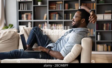 Lächelnder biracialer Mann mit Laptop zu Hause entspannen Stockfoto