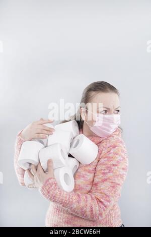 Eine Frau trägt eine Gesichtsmaske zum Schutz vor dem Corona-Virus und hat sich im Falle einer Quarantäne auf ihrem toilettenpapierstich aufgefüllt. FEM im mittleren Alter Stockfoto