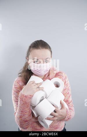 Eine Frau trägt eine Gesichtsmaske zum Schutz vor dem Corona-Virus und hat sich im Falle einer Quarantäne auf ihrem toilettenpapierstich aufgefüllt. FEM im mittleren Alter Stockfoto