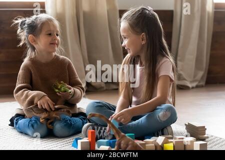 Liebenswerte kleine Kinder Schwestern, die mit Spielzeug im Wohnzimmer spielen. Stockfoto