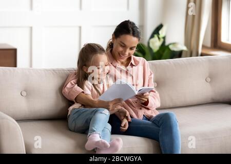 Junge Mixed-Race-Frau liest Buch für kleines Kind. Stockfoto