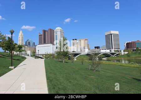 Alexander Park Downtown Columbus Ohio grüne Landschaft mit grünen Bäumen, Beton Gehweg, bunte Bäume City Skyline Struktur, blauer Himmel Stockfoto