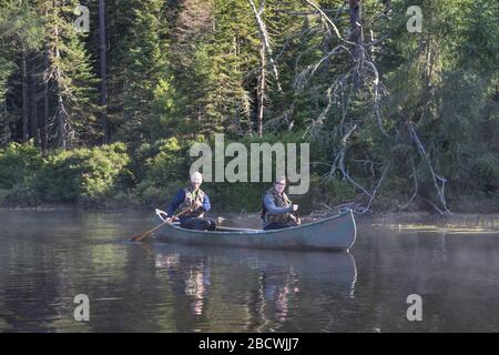 Ein junges Paar, das sich auf einem See im Kanu entspannt Stockfoto