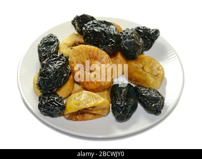 Trockene Früchte auf einem weißen Teller. Feigen und Pflaumen isoliert auf weiß. Stockfoto