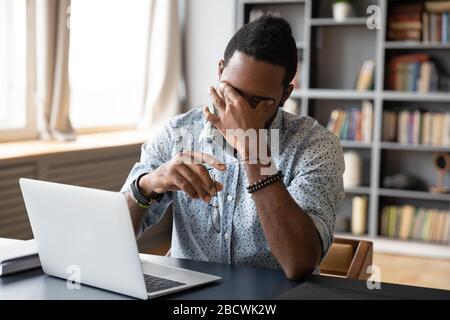 Erschöpfter afroamerikanischer Mann leidet am Arbeitsplatz unter Kopfschmerzen Stockfoto