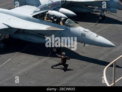 Ein Seemann der US-Marine führt die Flugvorkontrolle auf einer F/A-18F Super Hornet durch, die den Fighting Checkmates of Strike Fighter Squadron 211 zugewiesen ist, während er sich auf den Start vom Flugdeck des Flugzeugträgers der Nimitz-Klasse USS Harry S. Truman zur Unterstützung der Operation Inherent Resolve 10. März vorbereitet. 2020 im Arabischen Meer. Stockfoto