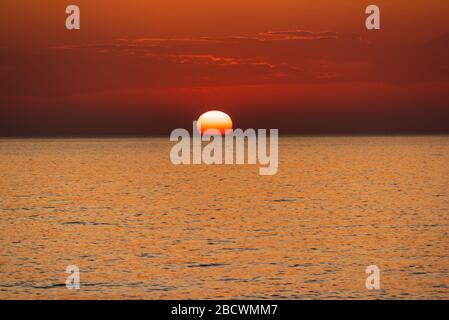 Wunderschöner, orangefarbener Sonnenuntergang am Meer, friedlich und idyllisch Stockfoto