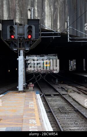 West Midlands Railway Class 323 323243, die mit einem quer durch die Stadt fahrenden Zug an der Birmingham New Street ankommt, der ein rotes Eisenbahnsignal passiert Stockfoto