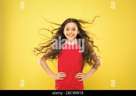 Perfekte locken. Kind süß Gesicht mit adorable curly Frisur. Kleines Mädchen lange Haare wachsen. Teen Mode Modell. Unterschied entdecken. Styling lockiges Haar. Friseur Tipp. Kind Mädchen lange gesund glänzendes Haar. Stockfoto