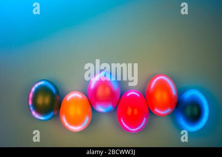 Kreative Fotos von bunten Eiern im Neonlicht auf grauem Hintergrund. Ostern Konzept. Flach Stil. Stockfoto