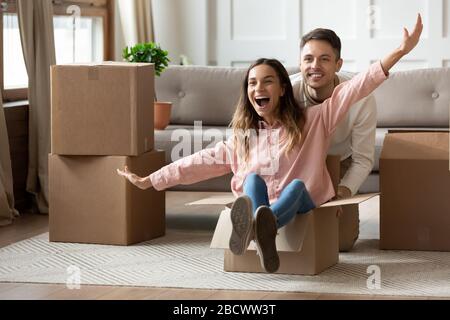 Überfreudiges Familienpaar, das sich in einem neuen Wohnzimmer lustig macht. Stockfoto