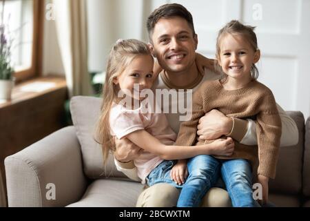 Porträt eines glücklichen Vaters, der zwei kleine Töchter in Runde hält. Stockfoto