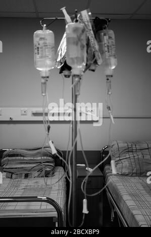 Leere Krankenhausbetten und Medikamente stehen für intravenöse Unschärfe in einem Krankenhauszimmer. Schwarzweißbild, vertikales Foto mit Vignettierung Stockfoto