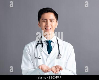 Portrait der männlichen asiatischen jungen Arzthand, die etwas zeigt Stockfoto