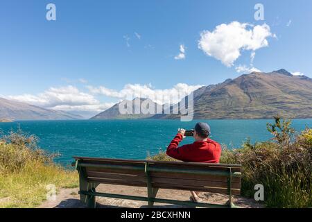 Ein Mann, der ein Foto von Lake Wakatipu von der Kelvin-Bahn gemacht hat Stockfoto