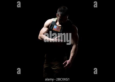 Bodybuilder Porträt des Soldaten mit Bulletproof West und US Flag auf schwarzem Hintergrund Stockfoto