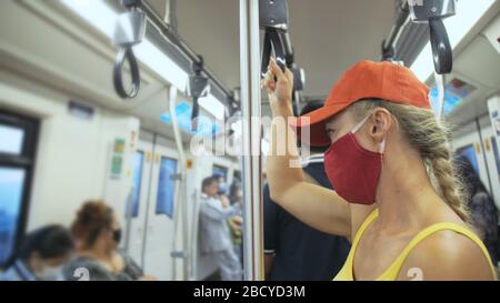 Frau fährt kaukasische Fahrt im überirdischen Zug airtrain mit Schutzmaske. Mädchen Tourist im airtrain mit Atemschutzmaske. Personenmaske. Stockfoto