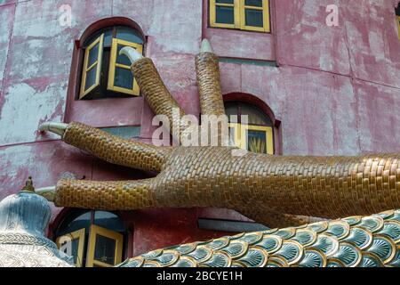 Eine riesige Klaue eines Drachen auf einer rosa Fassade mit Fenstern eines Gebäudes in einem buddhistischen Tempel, wat Samphran, Thailand. Stockfoto