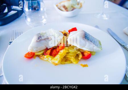 Gebackener Meeresbarsch mit gebratenem Gemüse und Kirschtomaten mit aromatischen Kräutern Stockfoto