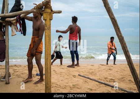 Junge indische Männer, die am Strand in Tiruchendur, Indien, spazieren gehen Stockfoto