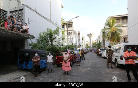 Colombo, Sri Lanka. April 2020. Menschen, die während der Aufführung auf sozialer Distanz zueinander beobachten.Mitglieder der Musikkapelle der Polizei Sri Lankas treten auf, um die Moral der Menschen im Kampf gegen die Verbreitung des SARS-COV-2-Coronavirus zu steigern. Credit: SOPA Images Limited/Alamy Live News Stockfoto