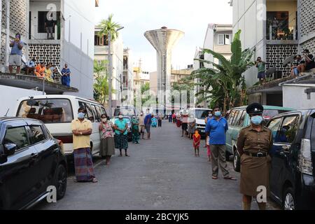 Colombo, Sri Lanka. April 2020. Menschen, die während der Aufführung auf sozialer Distanz zueinander beobachten.Mitglieder der Musikkapelle der Polizei Sri Lankas treten auf, um die Moral der Menschen im Kampf gegen die Verbreitung des SARS-COV-2-Coronavirus zu steigern. Credit: SOPA Images Limited/Alamy Live News Stockfoto