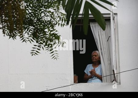 Colombo, Sri Lanka. April 2020. Eine ältere Frau lobt die Sri-lankische Polizei während der Aufführung aus ihrem Fenster.Mitglieder der Sri-lankischen Polizei-Musikkapelle treten auf, um die Moral der Menschen im Kampf gegen die Verbreitung des SARS-COV-2-Coronavirus zu steigern. Credit: SOPA Images Limited/Alamy Live News Stockfoto