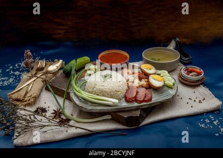 Rotes Schweinefleisch mit Reis (Kao Moo Dang): Rotes Grillpork im thailändischen Stil, Entenei und knuspriger Schweinebauch, geschnittene Gurke mit roter Soße und Brühe. Stockfoto