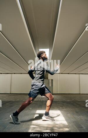 Seitenansicht des jungen, gutaussehenden Sportlers, der durch den Tunnel läuft Stockfoto