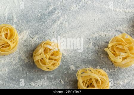 Handgemachte italienische Pasta - Tagliatelle auf grauem, florischem Hintergrund Stockfoto