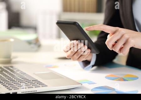 Nahaufnahme der Geschäftsfrau übergibt sich das Überprüfen des Smartphones an einem Schreibtisch im Büro