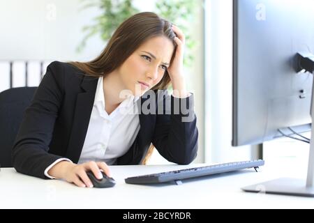 Besorgte Geschäftsfrau, die Online-Computerinhalte im Büro überprüft Stockfoto