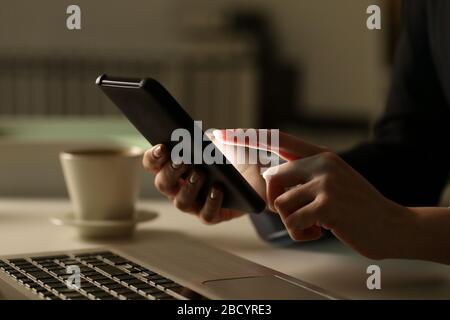 Nahaufnahme der Führungsfrau mit dem Smartphone nachts am Schreibtisch im Büro Stockfoto