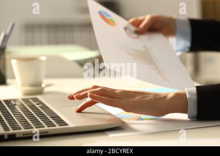 Nahaufnahme der Hände der Führungskraft Vergleich von Diagrammen Bericht auf Laptop nachts im Büro Stockfoto