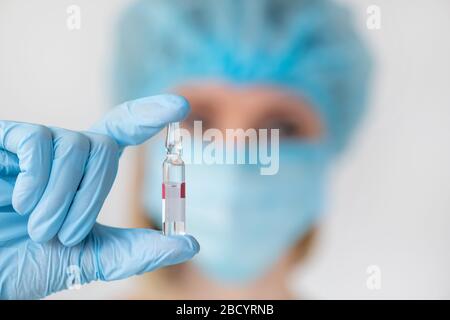 Ampulle zur Injektion in die Krankenschwesternhand. Medizinisches Glasfläschchen zur Impfung. Wissenschaftliche Ausrüstung, flüssiges Medikament oder Impfstoff. Medizinkonzept Stockfoto