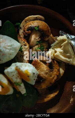 Köstliches Frühstück gekochtes Ei, Toast, Käse und Pilze in einem Tonteller auf Holzgrund. Mittelwarmes Ei. Stockfoto