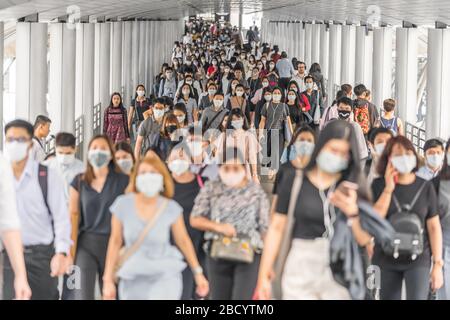 BANGKOK, THAILAND - MAR 2020: Menschenmenge von nicht erkennbaren Geschäftsleuten, die eine chirurgische Maske tragen, um einen Ausbruch von Coronavirus in der Hauptverkehrszeit zu verhindern Stockfoto