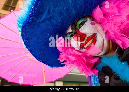 Eine Frau, verkleidet und als Clown bemalt, feiert tagsüber auf den Straßen den Karneval Stockfoto