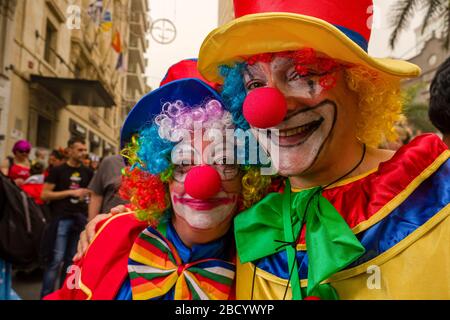 Ein Mann und eine Frau, als Clowns verkleidet und lächelnd, feiern tagsüber auf den Straßen während des Karnevals Stockfoto