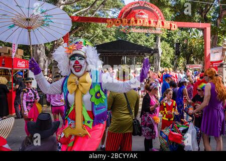 Eine Frau, verkleidet und als Clown bemalt, feiert tagsüber auf der Plaza del Príncipe de Asturias in den Straßen den Karneval Stockfoto