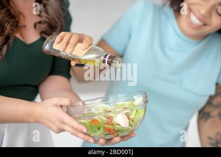 Hände von zwei Frauen würzen Ernährung Gemüsesalat. Stockfoto