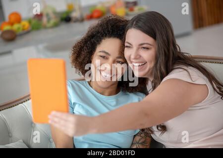 Zwei junge fröhliche Freundinnen nehmen selfie auf ein Tablet. Stockfoto