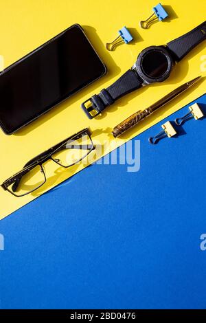 Flache Lay-Komposition für freiberufliche Blogger. Arbeitsplatz mit Stift, stylisches Smartphone, schwarze Uhr auf buntem Hintergrund.Geschäftskonzept. Modern Stockfoto