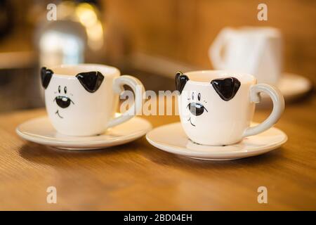 Zwei schwarze und weiße Tassen auf den kleinen Platten in der braunen Küche Stockfoto
