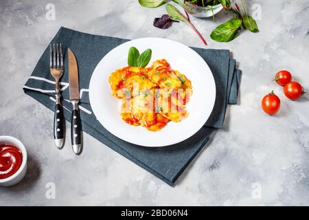 Ravioli mit Tomatensoße und Basilikum auf Betongrund. Köstliche Pasta Stockfoto