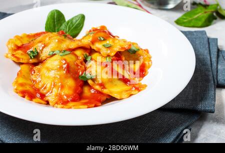 Ravioli mit Tomatensoße und Basilikum auf Betongrund. Köstliche Pasta Stockfoto