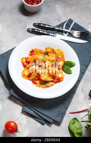 Ravioli mit Tomatensoße und Basilikum auf Betongrund. Köstliche Pasta Stockfoto