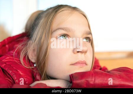 Nahaufnahme Portrait des jungen blonden Grünäugigen Mädchen. Sie legte ihr Kinn wehmütig und penibel auf einen nach oben blickenden Arm. Die Jugend ist voller Ideen, pl Stockfoto