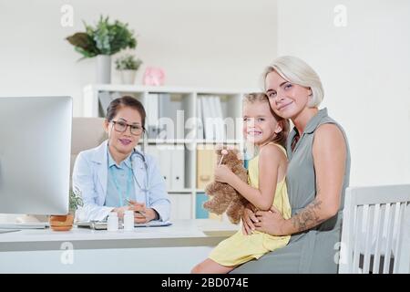 Glückliche Mutter und ihre kleine Tochter, die den Kinderarzt zur jährlichen körperlichen Prüfung besuchen Stockfoto